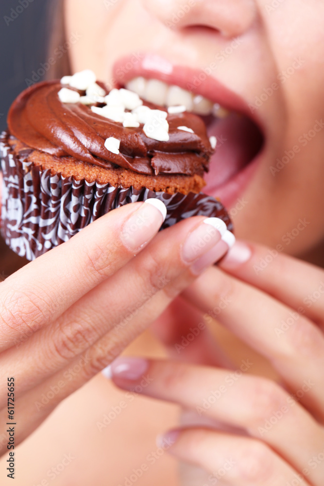 Closeup of woman eating chocolate cupcake