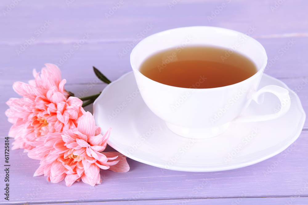 Pink chrysanthemums and cup of tea on wooden table
