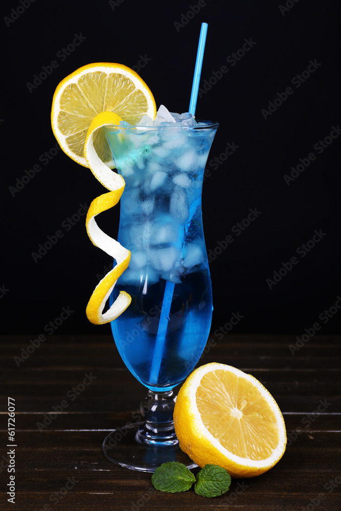 Glass of cocktail on table on black background