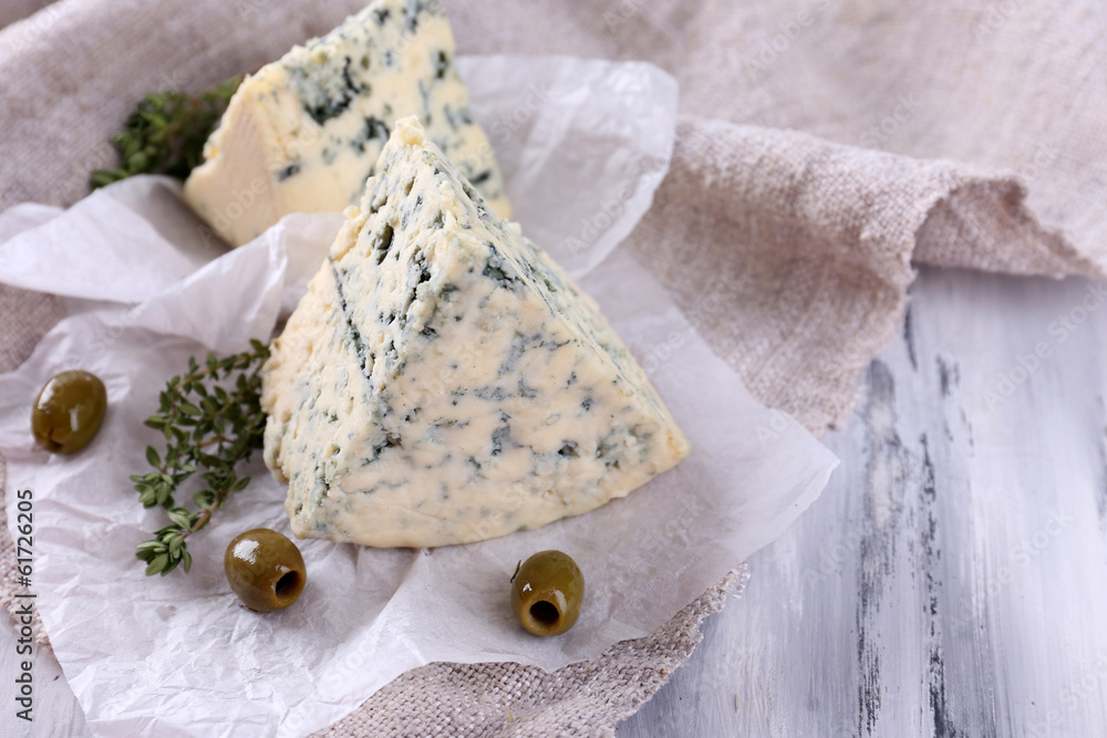 Tasty blue cheese with thyme and olives on paper