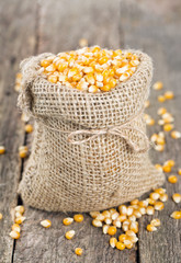 Wall Mural - corn in burlap bag on wooden surface