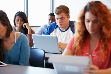 Wall Mural - male university student using laptop in classroom