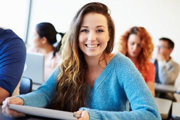 Wall Mural - female university student using digital tablet in classroom