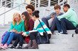 © Monkey Business - High School Students Sitting Outside Building With Phones