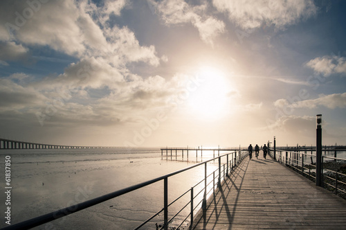 Obraz w ramie Bicycle riders on promenade in front of of Vasco da Gama Bridge.