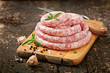 Fresh raw sausage on the old wooden background
