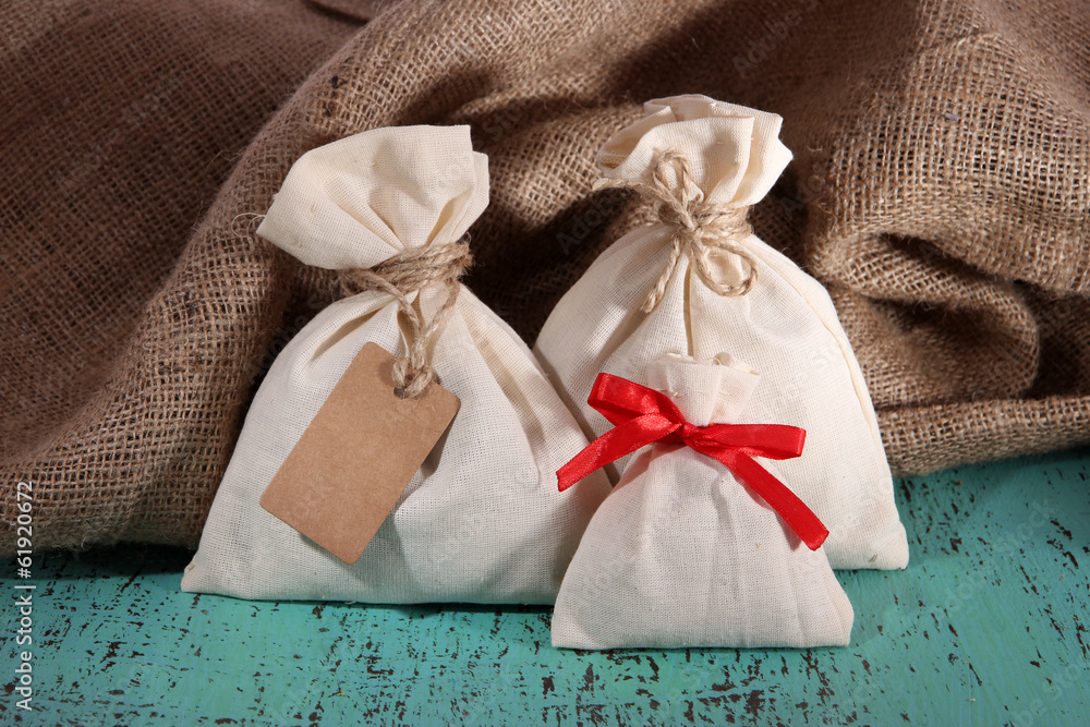 Sacks on color wooden table, on sackcloth background