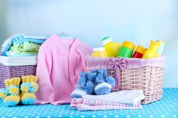 Wall Mural - Pile of baby clothes  in basket, on table on color background