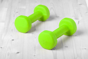 small green dumbbells on wooden surface