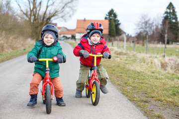 Two little twin toddler boys having fun on bicycles, outdoors