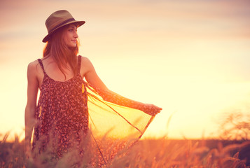 Beautiful woman in golden field at sunset