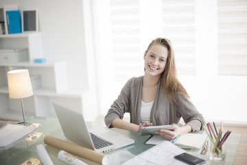 Wall Mural - beautiful young woman on the workplace using a digital tablet