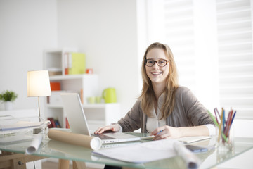 Wall Mural - beautiful young woman sitting at her desk in the workplace