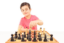 Young Boy Playing Chess Seated At A Table