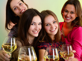  Happy young women friends touching the glasses with each other o