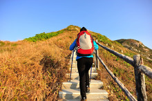 Young Woman Hiker Climbing Stone Stairs To Mountain Peak