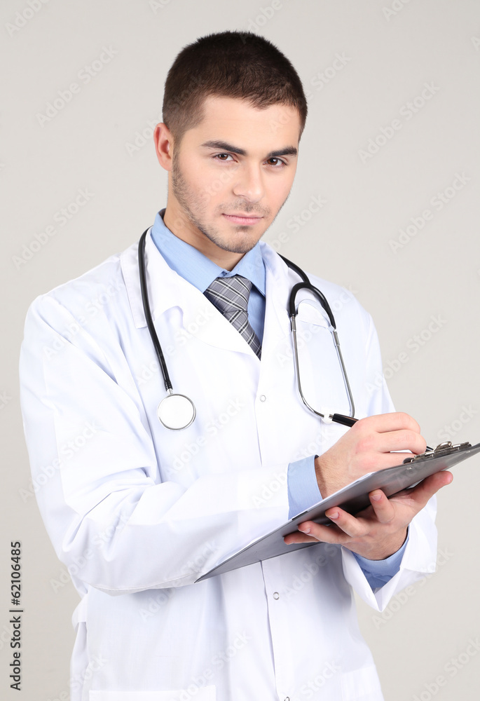 Male Doctor standing with folder, on gray background