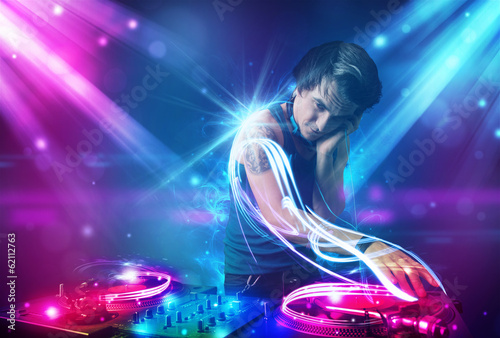 Plakat na papierze fotorealistycznym Energiczny dj miksujący muzykę z potężnymi efektami świetlnymi