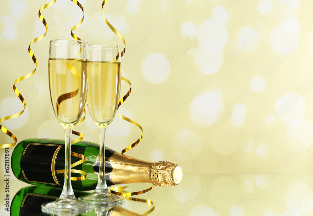 Glasses and bottle of champagne on light background
