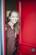 © jackfrog - beautiful young woman opening a red door to welcome someone