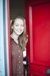 © jackfrog - beautiful young woman opening a red door to welcome someone