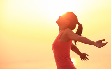 Wall Mural - cheering woman hiker open arms at sunrise beach