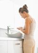 © Alliance - Young woman washing hands in bathroom