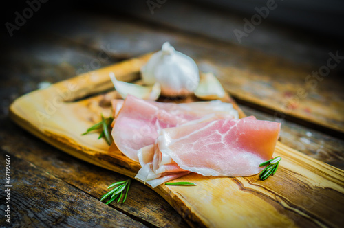 Board z aluminiowym obramowaniem Prosciutto z czosnkiem i rozmarynem na rustykalne drewniane tła