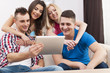 © gpointstudio - Happy friends spending free time and using digital tablet