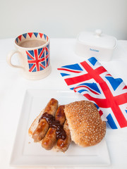 English sausage sandwich with, brown sauce, cup of tea and flag