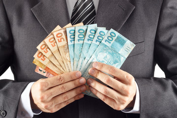 A businessman in a suit showing brazilian money