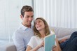 © lightwavemedia - Young couple reading book on couch