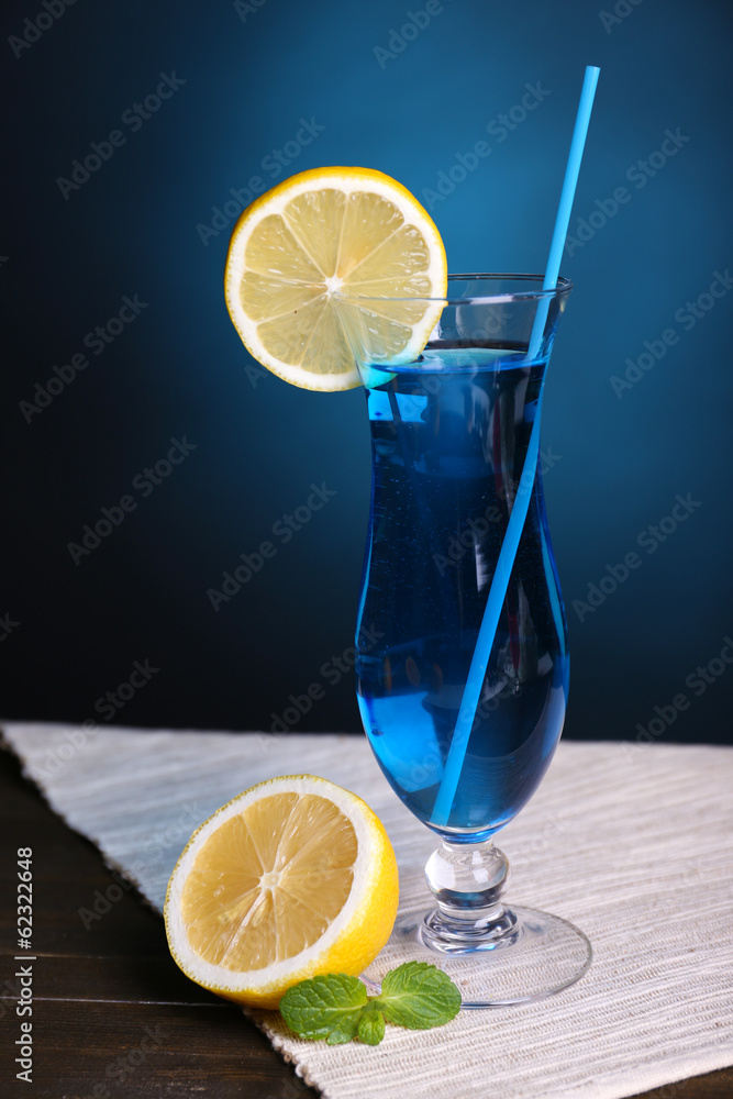 Glass of cocktail on table on dark blue background