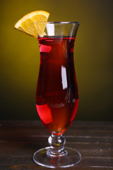 Poster - Glass of cocktail on table on dark yellow background