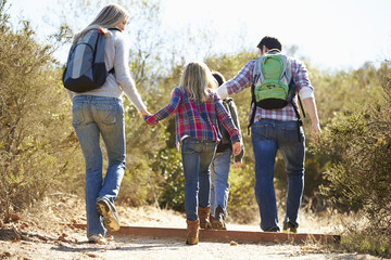 Wall Mural - Rear View Of Family Hiking In Countryside Wearing Backpacks