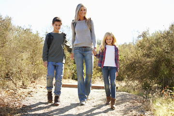 Wall Mural - Mother And Children Hiking In Countryside Wearing Backpacks