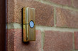 Brass-coloured doorbell on a brick wall