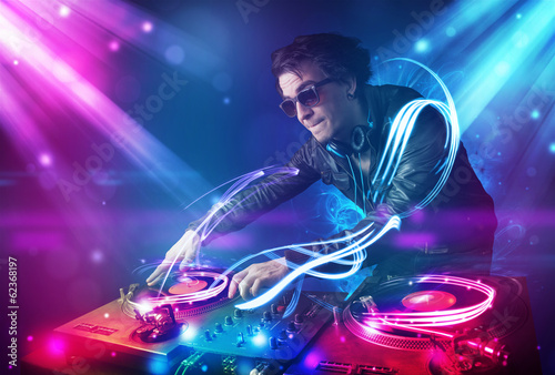 Plakat na papierze fotorealistycznym Energiczny dj miksujący muzykę z potężnymi efektami świetlnymi