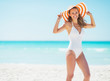 © Alliance - Portrait of smiling young woman in hat on beach