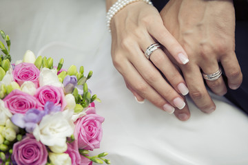 Hands of the groom and the bride with wedding bouquet