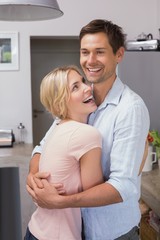 Wall Mural - Happy young couple embracing in the kitchen