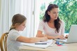 © lightwavemedia - Girl doing homework while mother using laptop at table