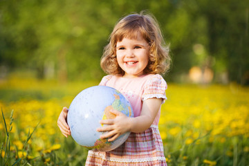 Little smiling girl with a globe in a summer field