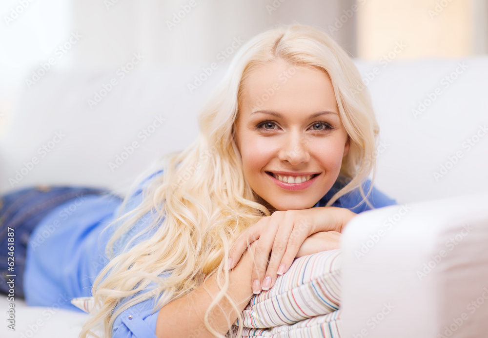 smiling young woman lying on sofa at home