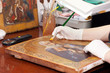 restorer works on old gilded icon with brush