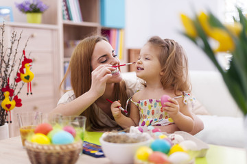 Mother and her baby have fun while painting easter eggs