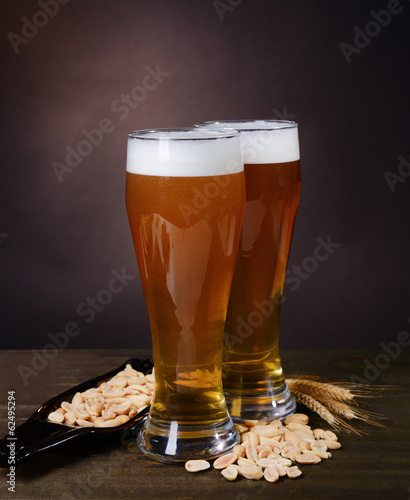 Fototapeta na wymiar Glasses of beer with snack on table on dark background