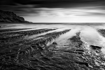 Beautiful black and white landscape of rocky shore at sunset