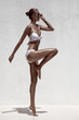 Beautiful tan female model posing in bikini and sunglasses. Agai