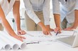 © lightwavemedia - Mid section of business people working on blueprints at office